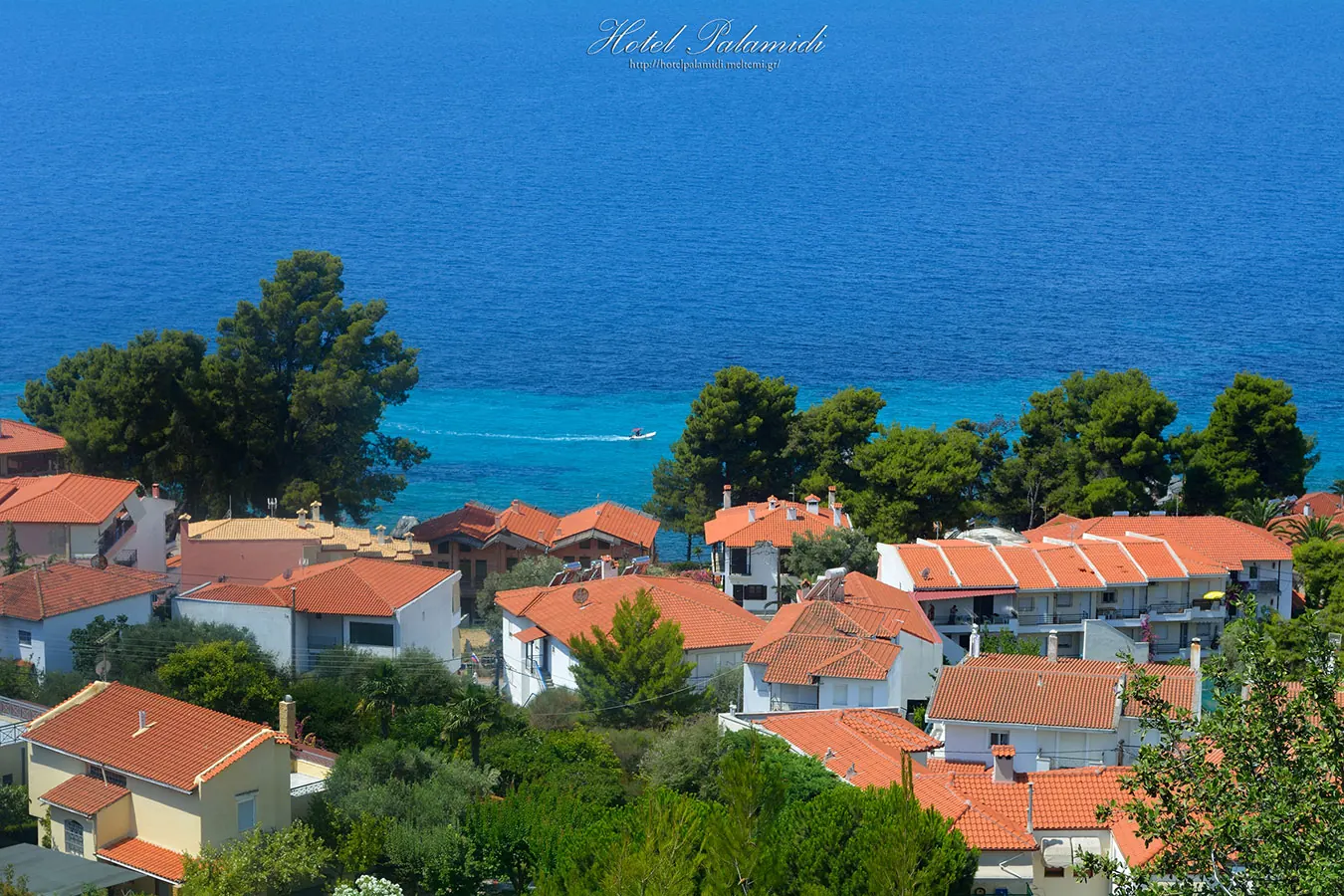 Red roofs of Loutra village among pine trees, the turquoise sea behind