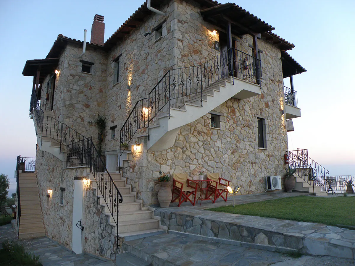 The stone-built Palamidi building at dusk, with outdoor stairs and lit windows