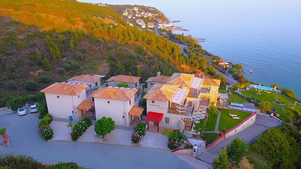 Aerial view of Koumaros Villas on the hillside in evening light, the sea beyond